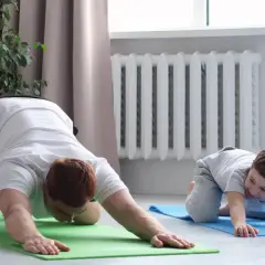 Ojciec i syn wykonują ćwiczenia na lordozę szyjną na macie.