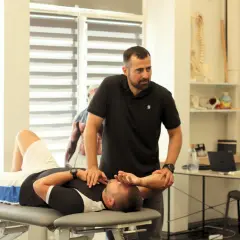 Fizjoterapeuta wykonuje badanie pacjenta na kozetce, ćwicząc diagnozę różnicową.