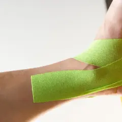 Taping na stopę koślawą u dziecka, zielona taśma kinezjotapingowa stabilizuje staw skokowy.