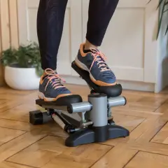 Ćwiczenia na stepperze w domu. Osoba w sportowych butach wykonuje trening, który angażuje mięśnie nóg i pośladków.