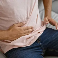 Mężczyzna trzyma się za brzuch, odczuwając ból w jelicie cienkim.
