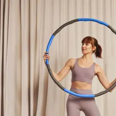 Kobieta z rudymi włosami trzyma hula hop z obciążeniem, gotowa do treningu.