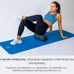 Kobieta wykonuje ćwiczenia na mięsień gruszkowaty, używając wałka do masażu na macie.