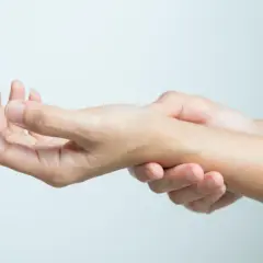 Dłoń masuje nadgarstek, który boli po stłuczeniu ręki po upadku.