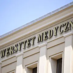 Napis "Uniwersytet Medyczny" na jasnej fasadzie budynku pod błękitnym niebem.