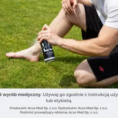 Mężczyzna stosuje spray chłodzący przeciwbólowy na nogę siedząc na trawie.