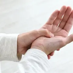 Dłoń masuje punkt między kciukiem a palcem wskazującym, co może pomóc w łagodzeniu bólu głowy dzięki akupresurze.
