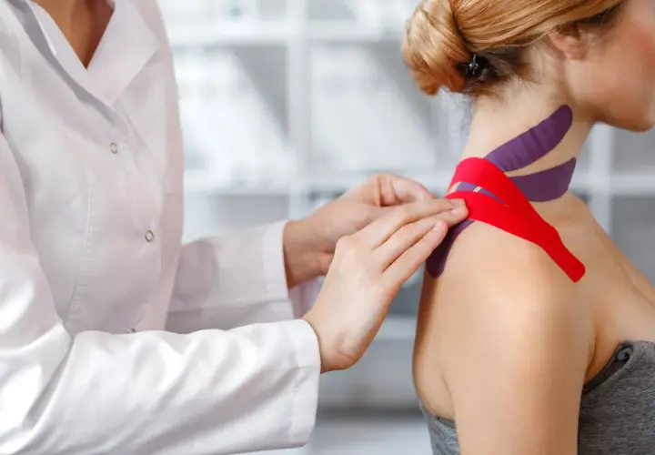 Fizjoterapeuta aplikuje tejpy na szyję i ramię pacjentki. Czy tejpy mogą zaszkodzić? Prawidłowo zaaplikowane są bezpieczne.