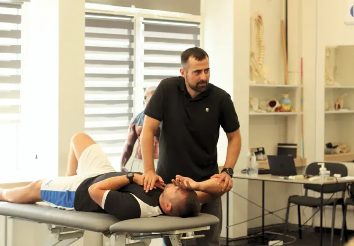 Fizjoterapeuta wykonuje badanie pacjenta na kozetce, ćwicząc diagnozę różnicową.