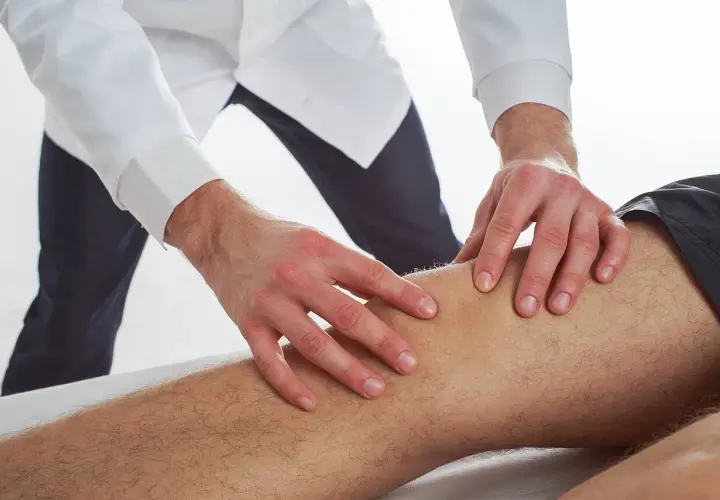 Terapeuta wykonuje delikatne ruchy na nodze pacjenta, co ilustruje, na czym polega terapia Bowen'a.